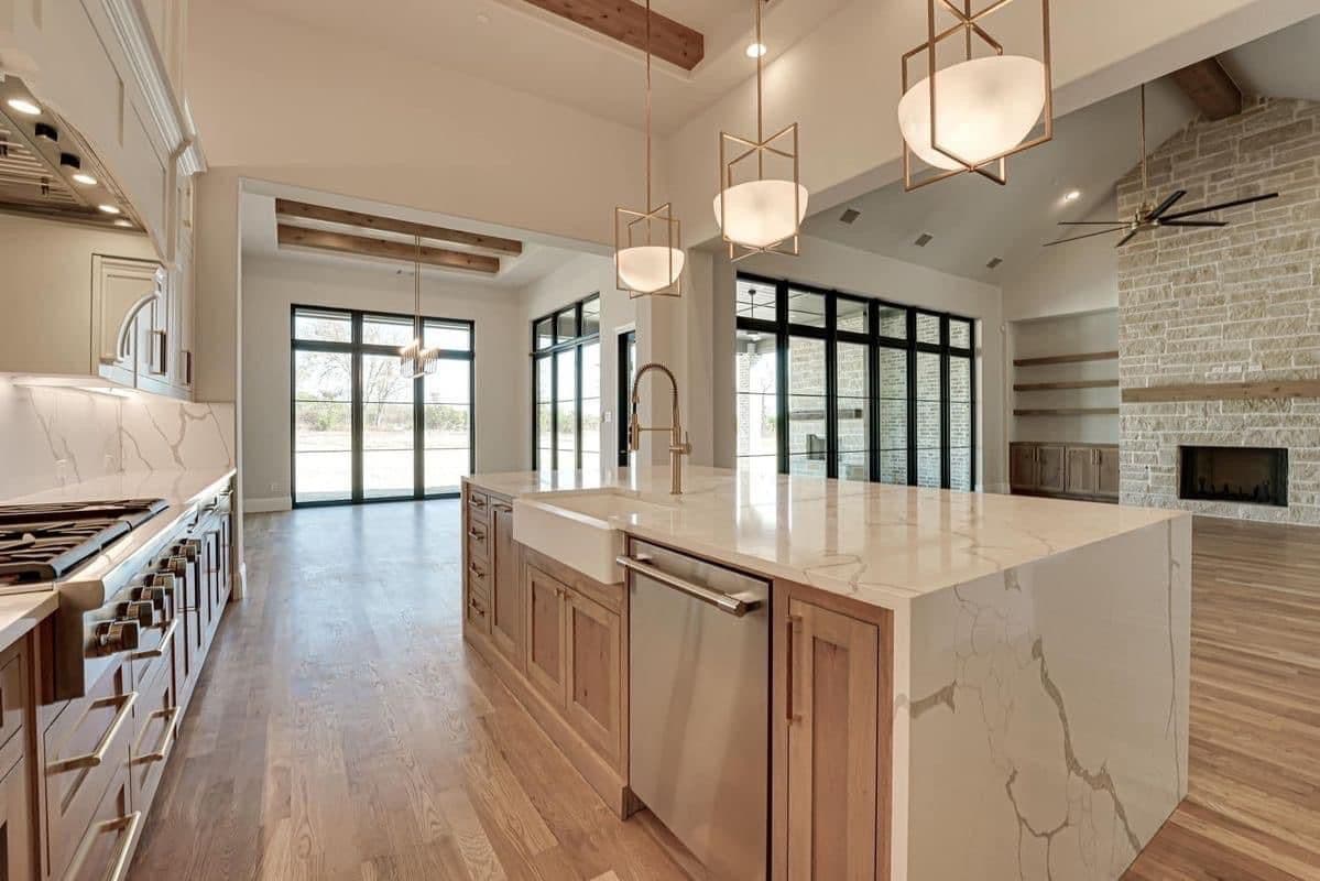 Bright kitchen with a marble island, wood cabinets and pendant lights