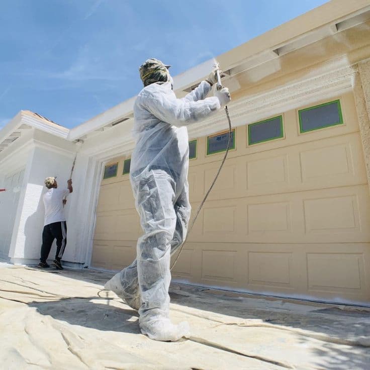 Painter spraying the exterior of a house